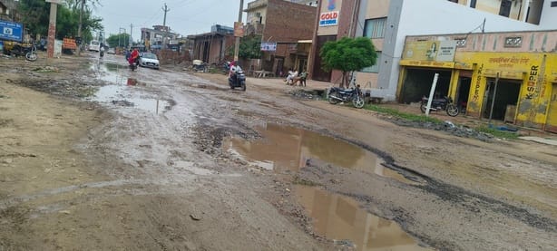 पूंडरी मार्ग पर बारिश के बाद बने गड्ढों में भरा पानी, कीचड़ के बीच से गुजरते वाहन चालक।