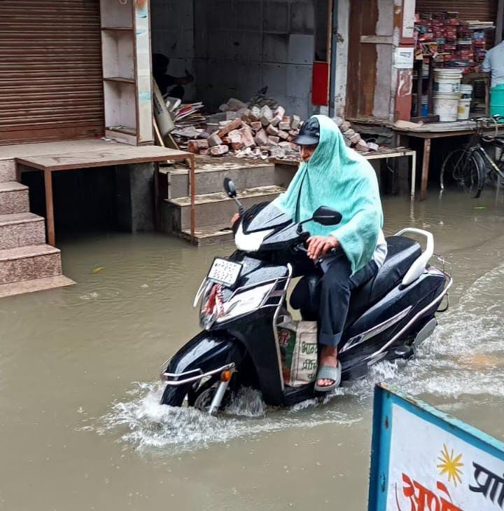 शामली के बड़ा बाजार में बारिश के बाद जलभराव के बीच से जाते बाइक सवार। संवाद
