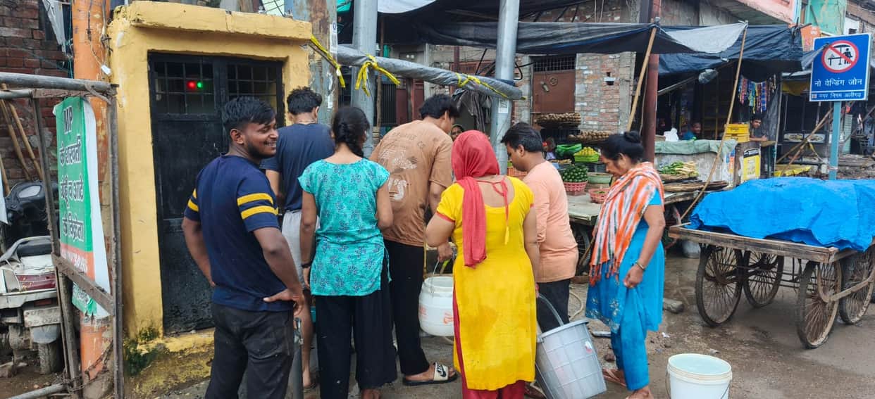 Household taps run dry; people step out with buckets amidst the rain
