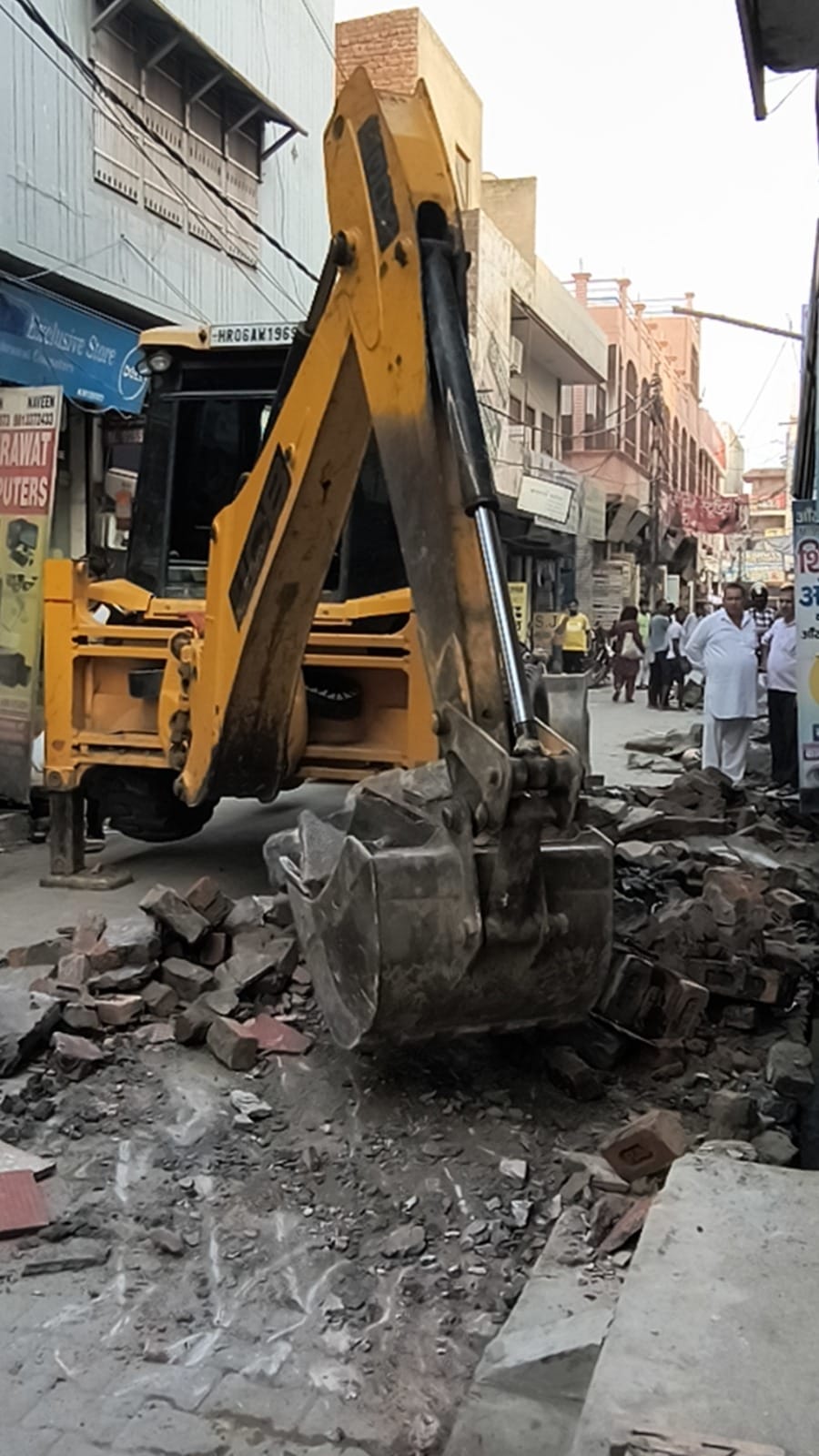 दुकानों के बाहर बने थड़े तोड़ती जेसीबी। संवाद
