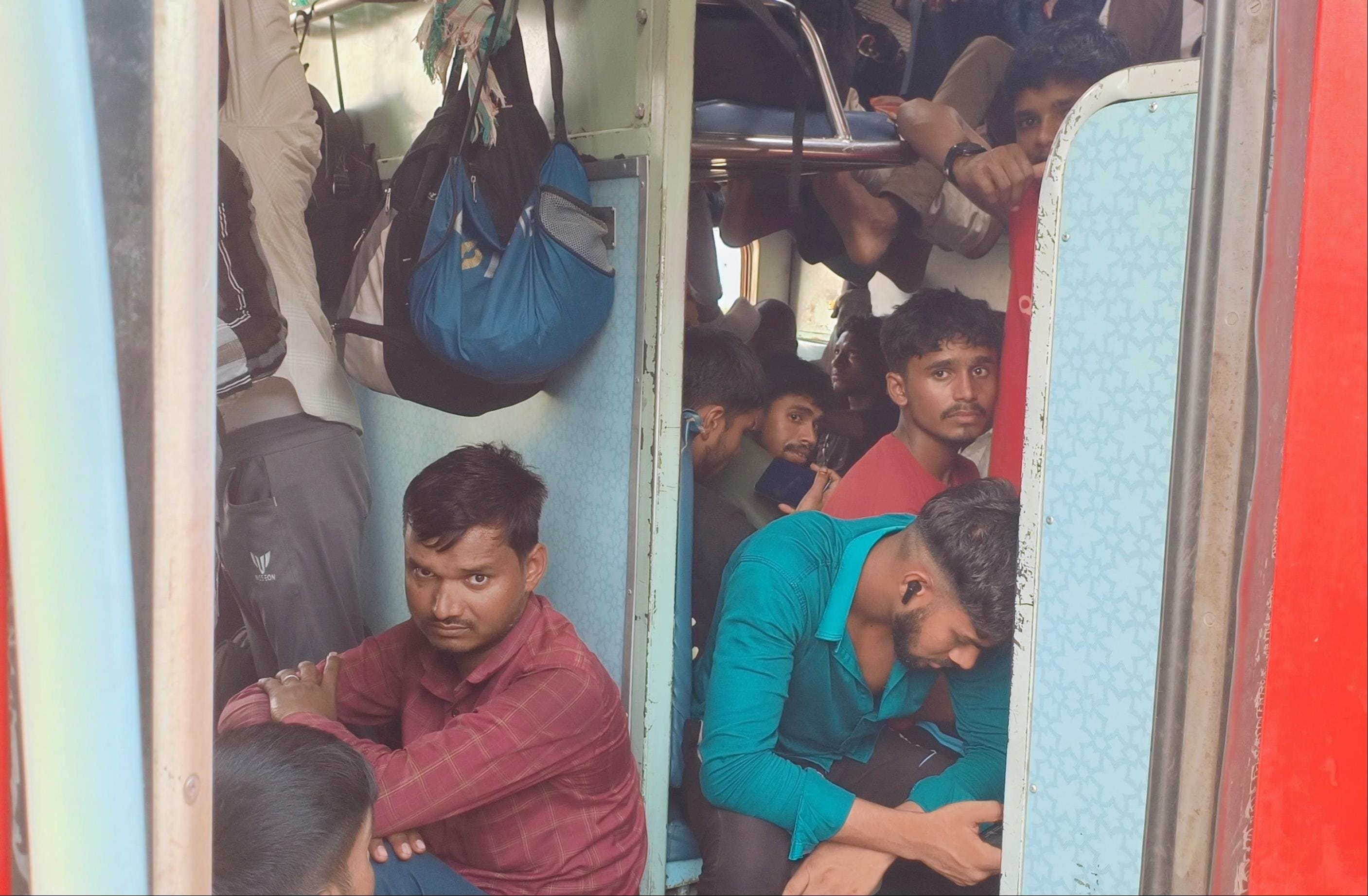 मुंबई जाने वाली ट्रेन में सीट न मिलने पर गेट पर बैठकर सफर करते यात्री संवाद
