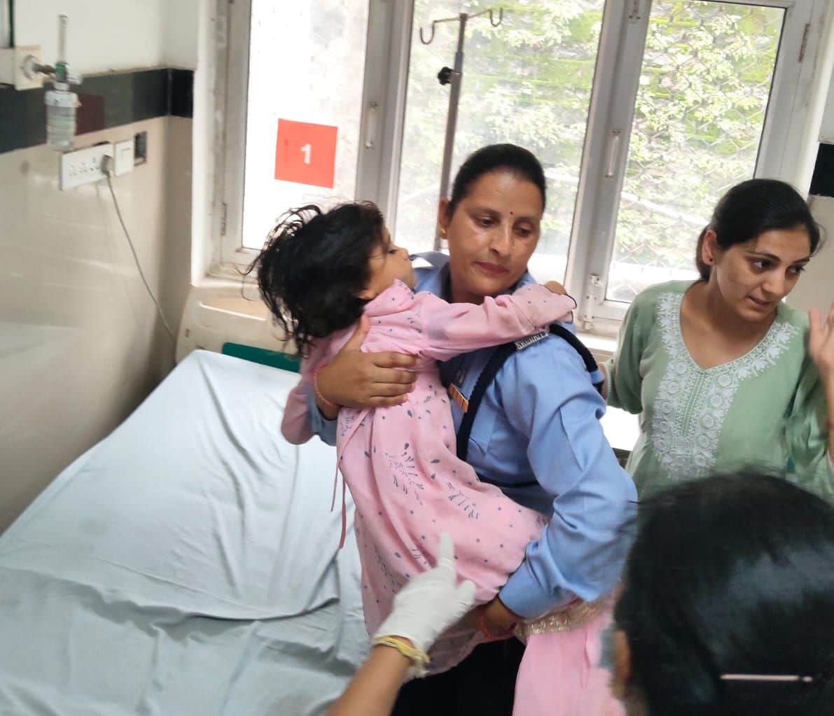 मेडिकल कॉलेज में निजी सुरक्षा कर्मी घायल बच्ची को गौद में उठाकर ले जाती हुई। संवाद।