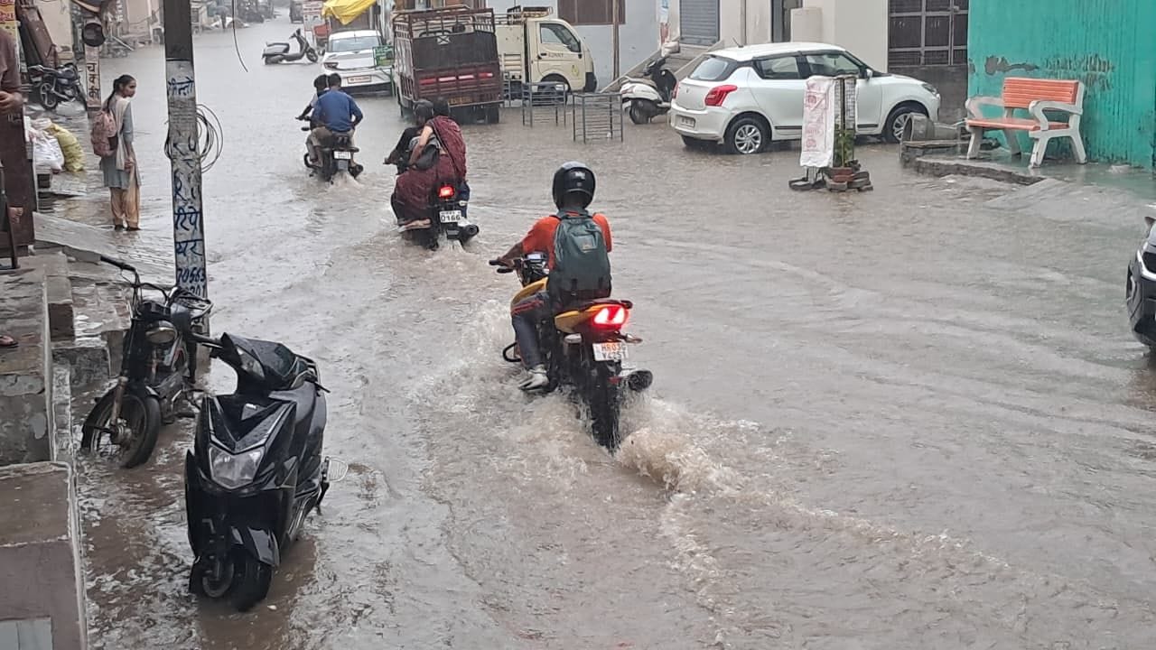 शहर के हनुमान गेट पर जमा  बारिश के पानी में से गुजरते बाइक चालक।