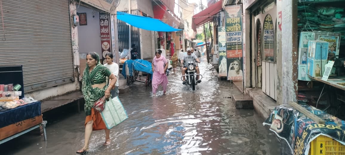 Rainwater floods markets and streets; pedestrians face difficulties.