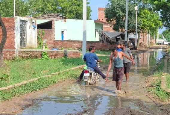फोटो10-पटियाली विकास खंड के गांव नगला मोहन में मुख्य मार्ग पर हुए जलभराव व कीचड़ के बीच से होकर