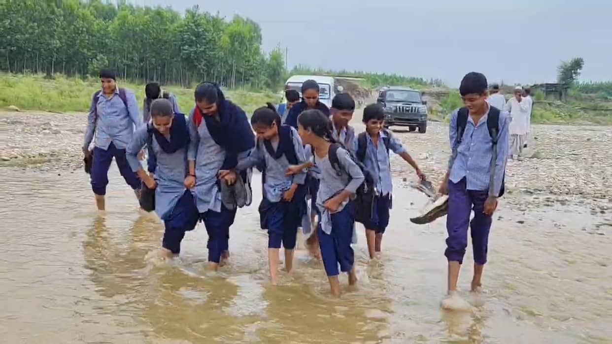 Children from two villages cross a seasonal river to go to school