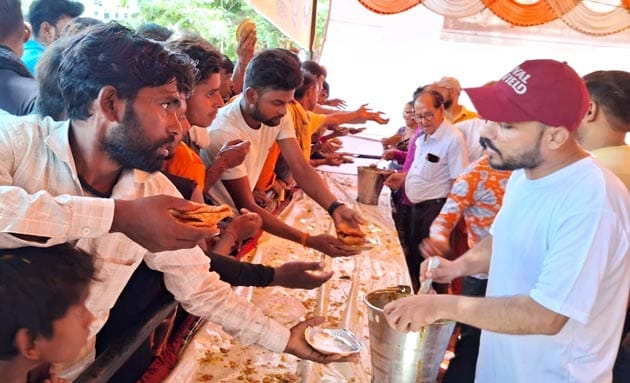 भंडारे में कांवड़ियों को सब्जी- पूडी और हलुवा बांटते देवनागरी कॉलेज के प्रबंधक। संवाद