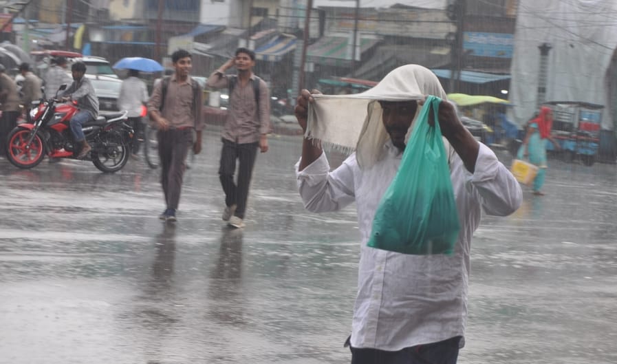 हापुड़ में बारिश के तोलिया ओढ़कर जाता व्यक्ति। संवाद