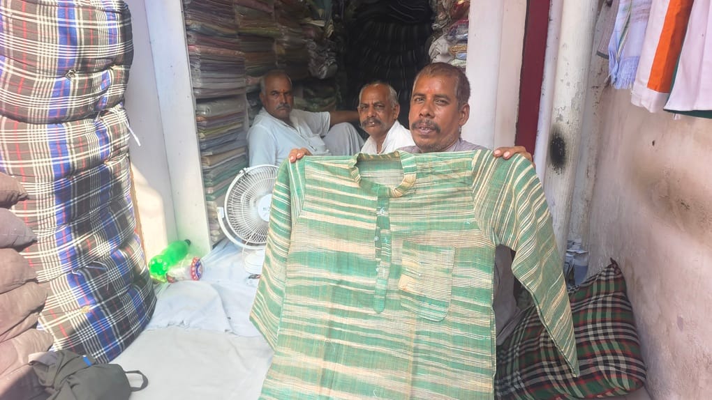 खादी की दुकान पर कुर्ता दिखाता दुकानदार। संवाद 
