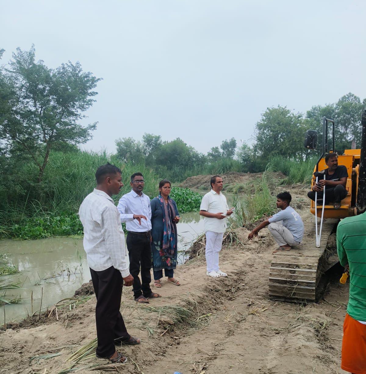 पानी निकालने में लगी पोकलैंड मशीन व मौजूद अधिकारी।संवाद