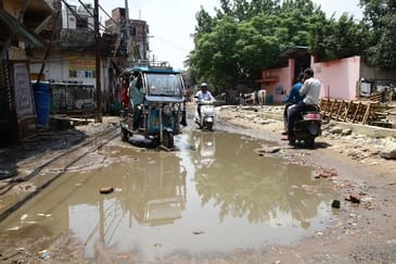 बिहारीपुरा की टूटी सड़क पर सीवर लाइन&nbsp;का पानी से हुए जलभराव से गुजरते वाहन। संवाद