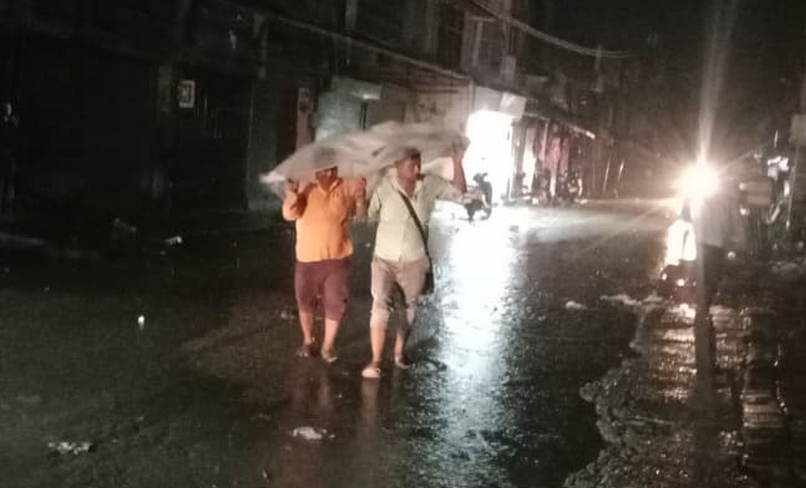 बारिश से बचने के लिए पन्नी ओढ़कर जाते लोग। संवाद