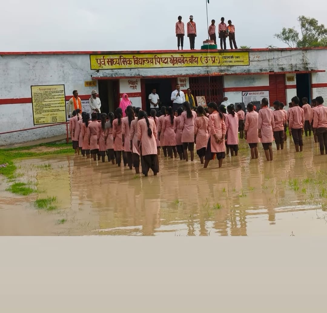 फोटो-29 - बबेरू के गांव पिष्टा में ध्वजारोहण के दौरान गंदे पानी में खड़े छात्र। स्रोत - इंटरनेट
