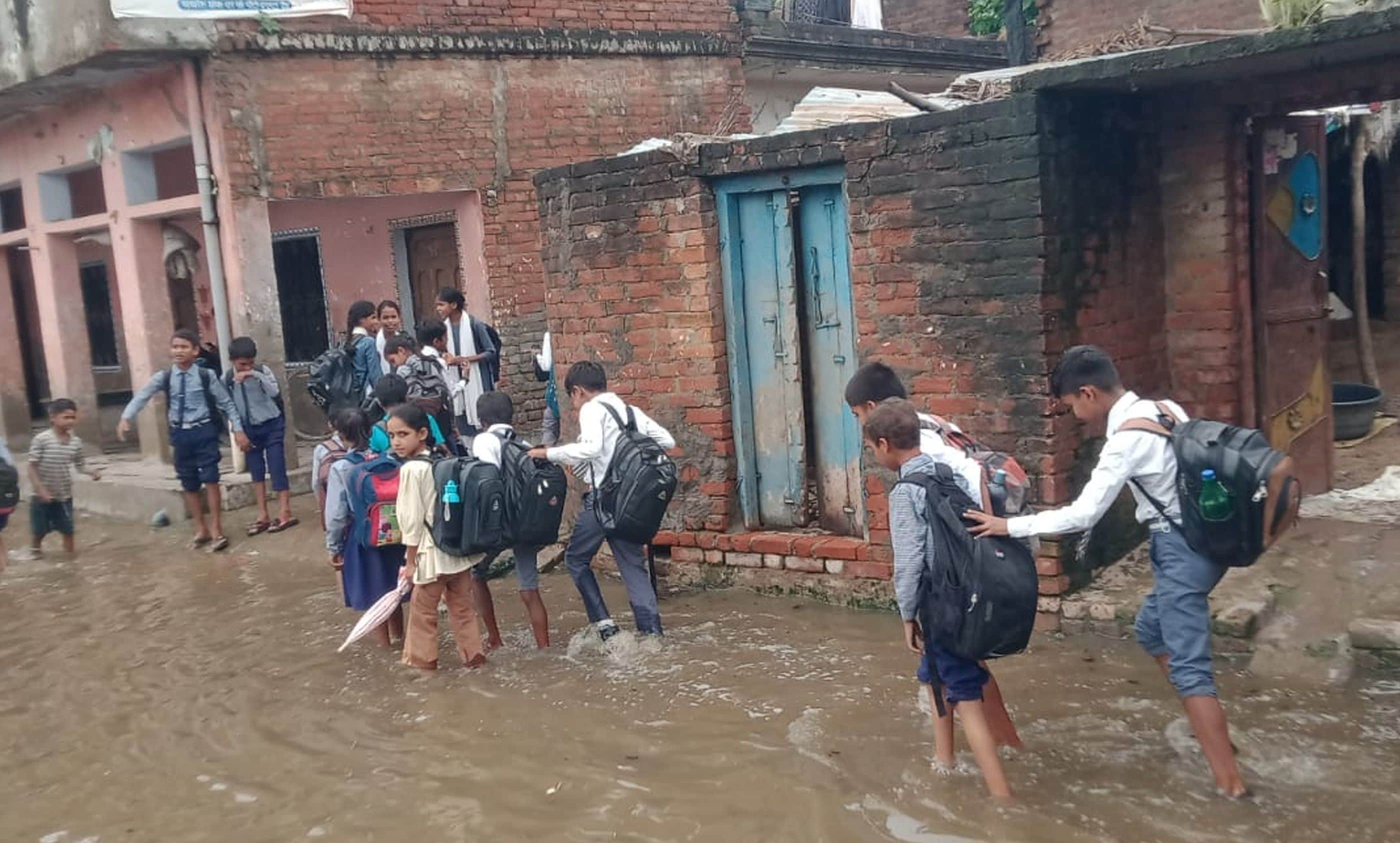 फोटो-41- बरसात से खखरूरू में व्याप्त जलभराव से होकर स्कूल से घर जाते बच्चे। संवाद