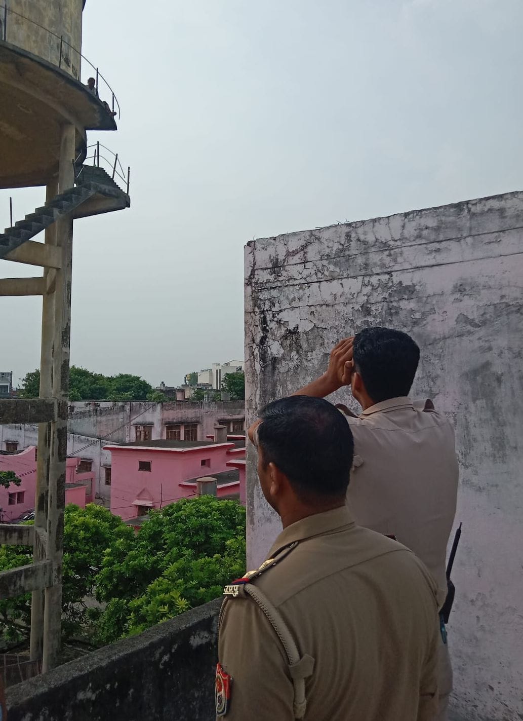 जिला अस्पताल में ओवरहेड टैंक पर चढ़ी महिला छुट्टो से बात करने की कोशिश करते पुलिस कर्मी। संवाद