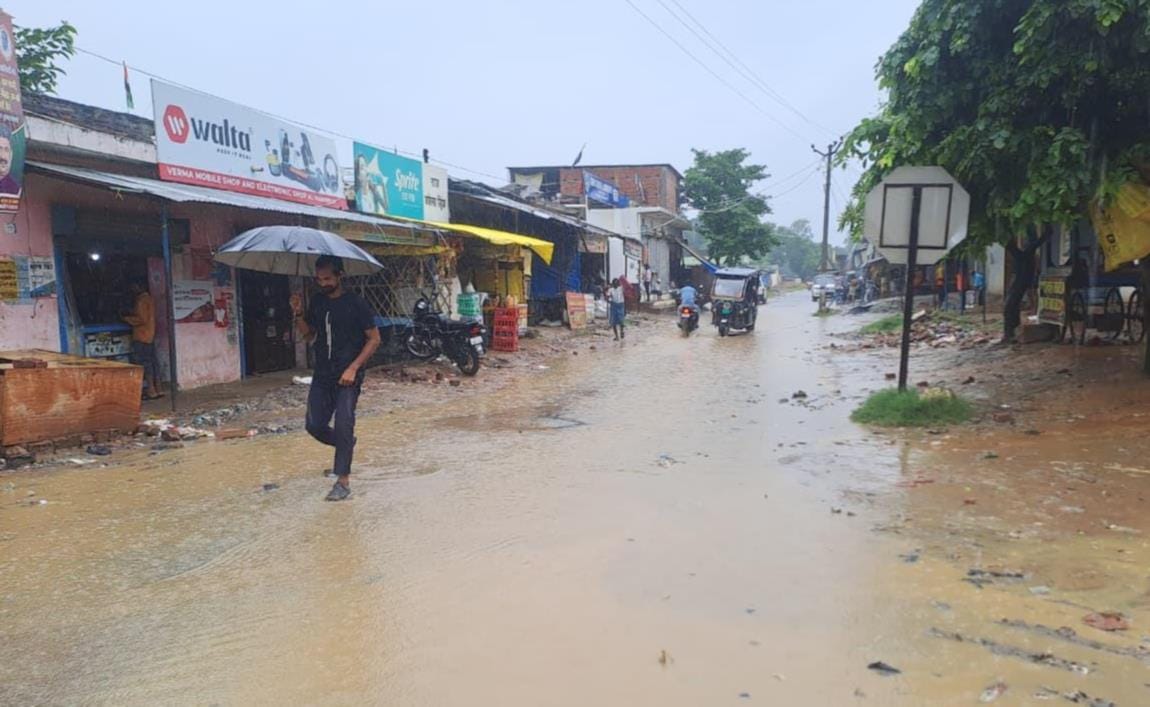 मधवापुर घाट के पास कटान करती राप्ती नदी,बारिश के बीच छाता लेकर निकलता व्यक्ति।
