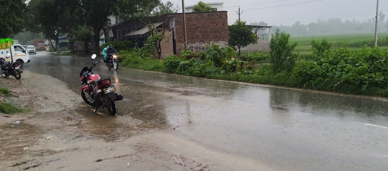  सोमवार को हुई बारिश के बीच निकलते लोग। संवाद