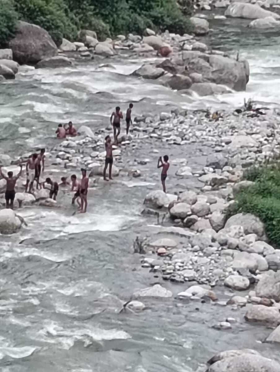 चामुंडा माता मंदिर के साथ बहती बाणगंगा में नहाते श्रद्धालु।  -स्रोत : जागरूक पाठक