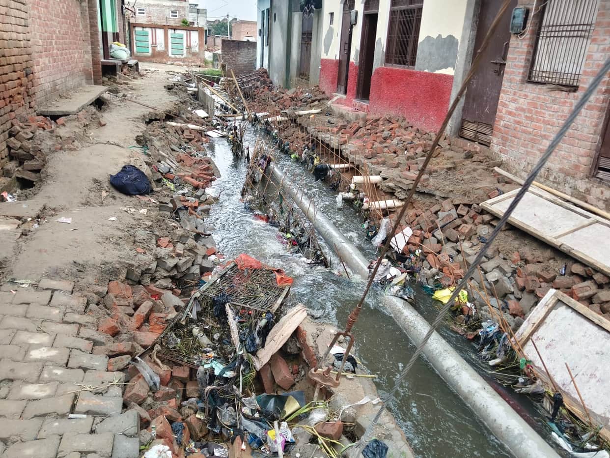 Rain washes away under-construction drain mesh; residents distressed as paving stones are dislodged.