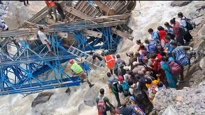 People risking their lives to cross the mountain stream after the Bailey bridge collapsed.