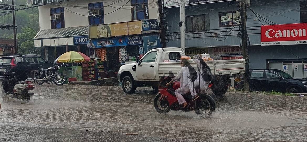  बुधवार को हो रही तेज बारिश के दौरान शहर के पुराने राजमार्ग से गुजरते दुपहिया वाहन