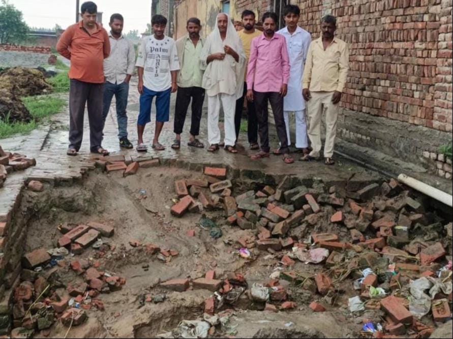 चौसाना में बारिश में उखड़े खड़ंजे को दिखाते ग्रामीण। ग्रामीण