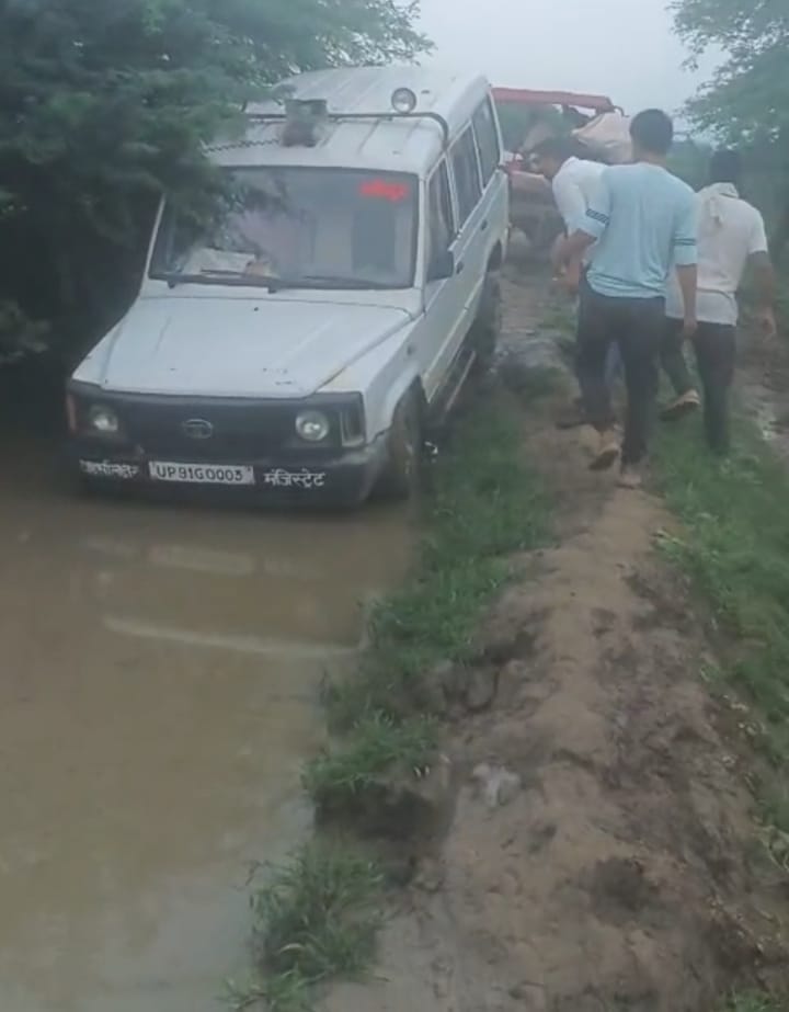 Official's car stuck in the mud; villagers say, "Look at the trouble."