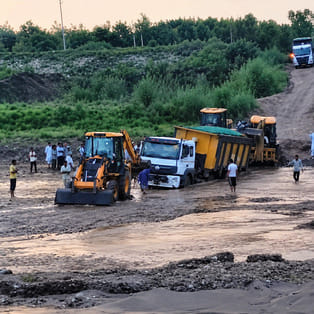 No bridge over the Boli River; people crossing while risking their lives; truck gets stuck.