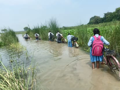 खरैलिया ढाला से सोनौरा के पास जान जोखिम में डालकर कमर भर पानी से घर जाते स्कूली बच्चियां। संवा