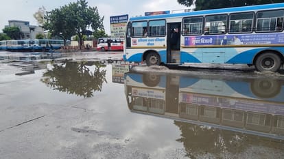 शहर के बस स्टैंड पर भरे पानी से गुजरती बस। संवाद