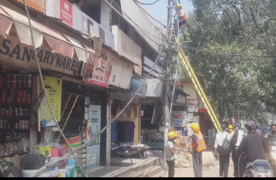  बाजार में बिजली कर्मी तारों को बदलते।  