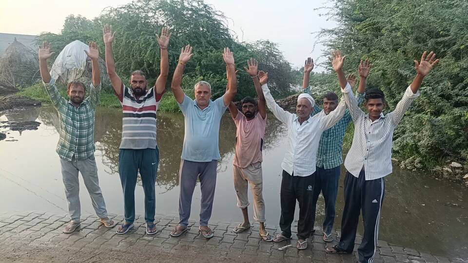 गली में जल भराव की समस्या से परेशान ग्रामीण रोष जताते हुए। संवाद