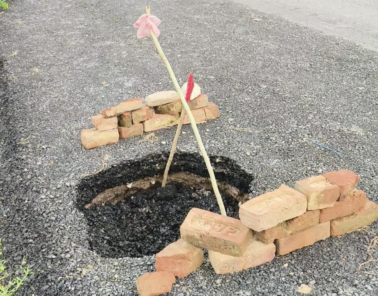 A deep pothole in the middle of the wide road poses a constant risk of accidents.