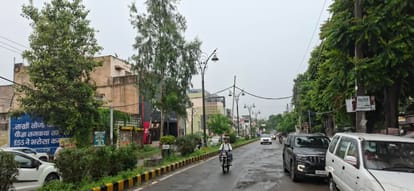 सुबह बारिश के दौरान शहर की गोबिंदपुरी रोड से गुजरते लोग। संवाद
