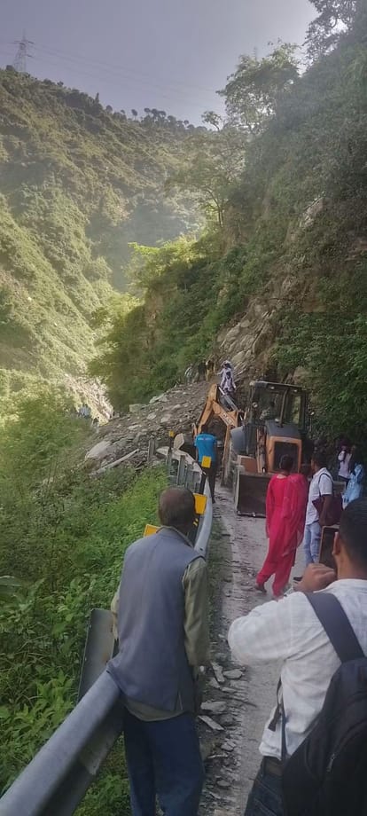 पंडोह-बाखली मार्ग पर पहाड़ी से गिरे मलबे के ऊपर से जाते स्थानीय लोग व बहाली में जुटी मशीनरी। स्