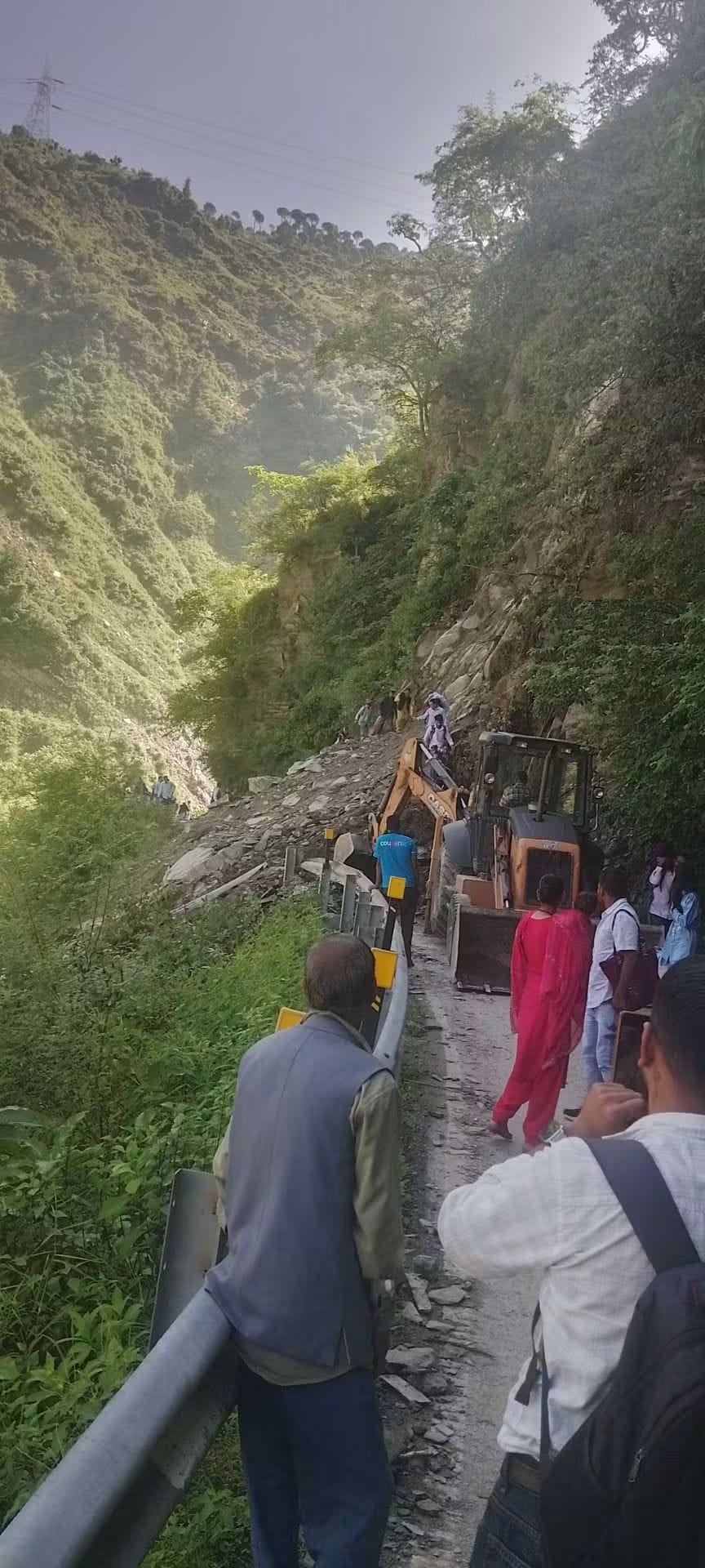 पंडोह-बाखली मार्ग पर पहाड़ी से गिरे मलबे के ऊपर से जाते स्थानीय लोग व बहाली में जुटी मशीनरी। स्