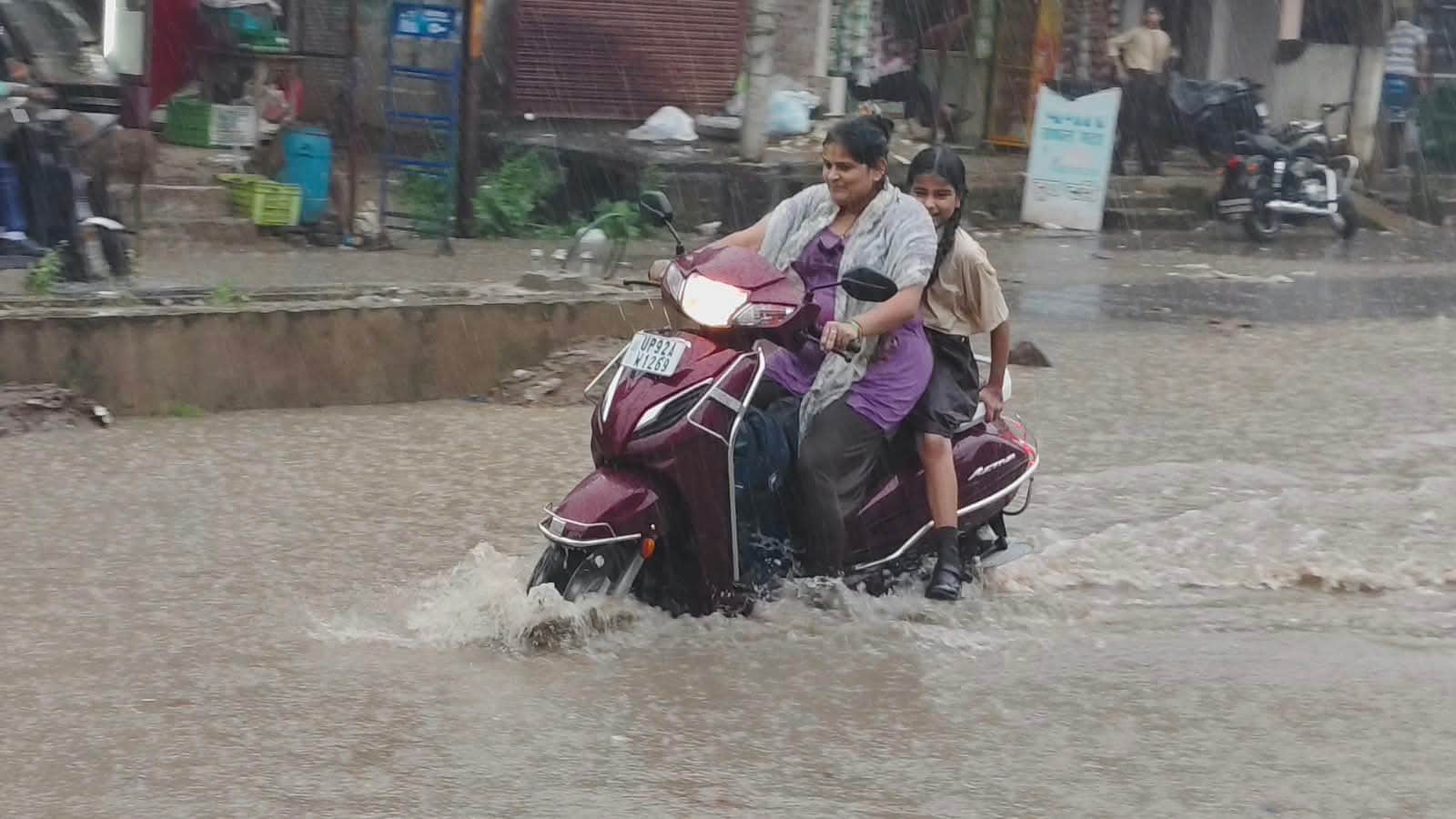 फोटो-26-इंदिरा नगर में जलभराव के बीच बेटी को स्कूल से लेकर लौटती महिला।