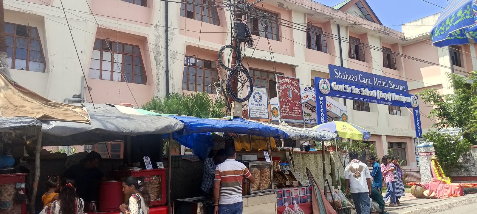 हमीरपुर मुख्य बाजार में प्रवासियों द्वारा खंभे के साथ तिरपाल डालकर सजाई दुकानदारी। संवाद