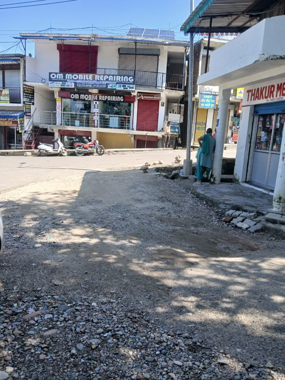 Fear of accidents at Tauni Devi Hospital Chowk due to a broken drain and scattered gravel.