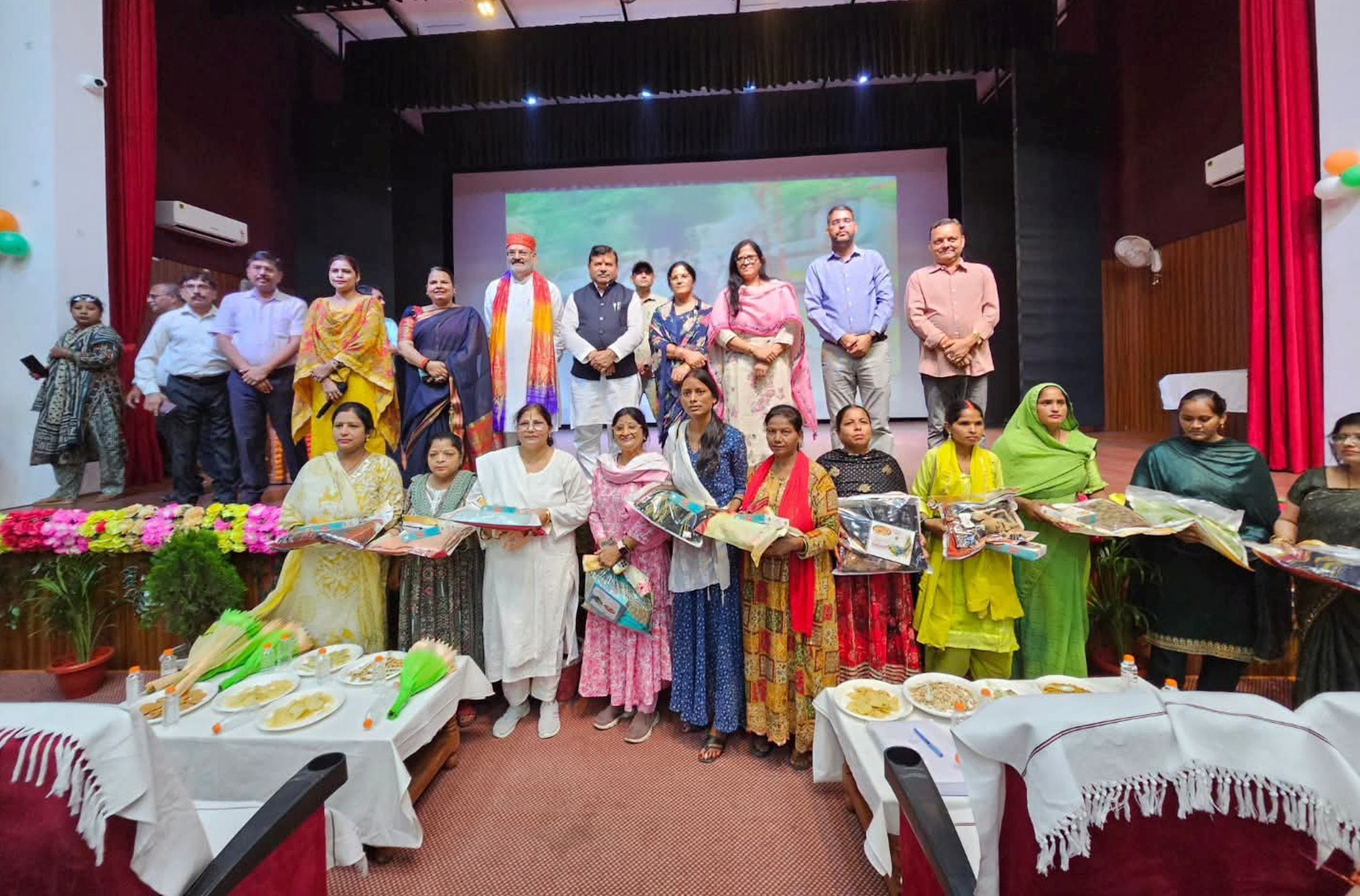 कार्यक्रम में मिठाई व साड़ी का उपहार मिलने के बाद मुख्य अतिथि के साथ मौजूद महिलाएं।
