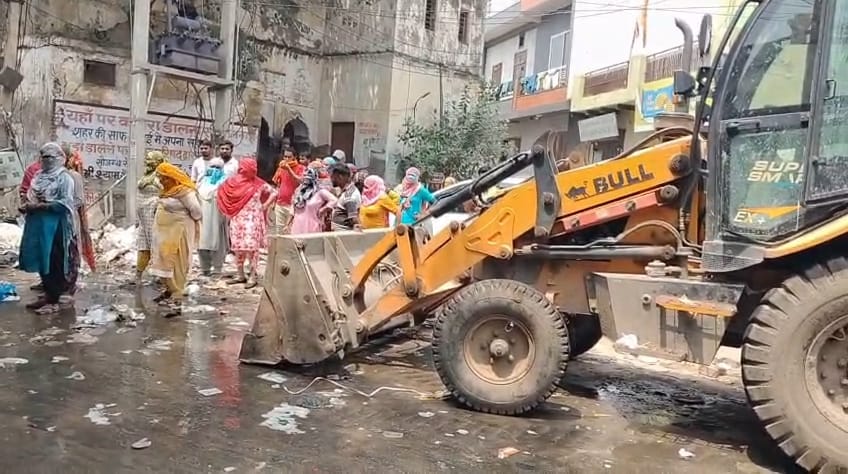 Female sanitation worker clashes with Municipal Council team arriving to collect garbage; stands in front of the tractor to block the pickup
