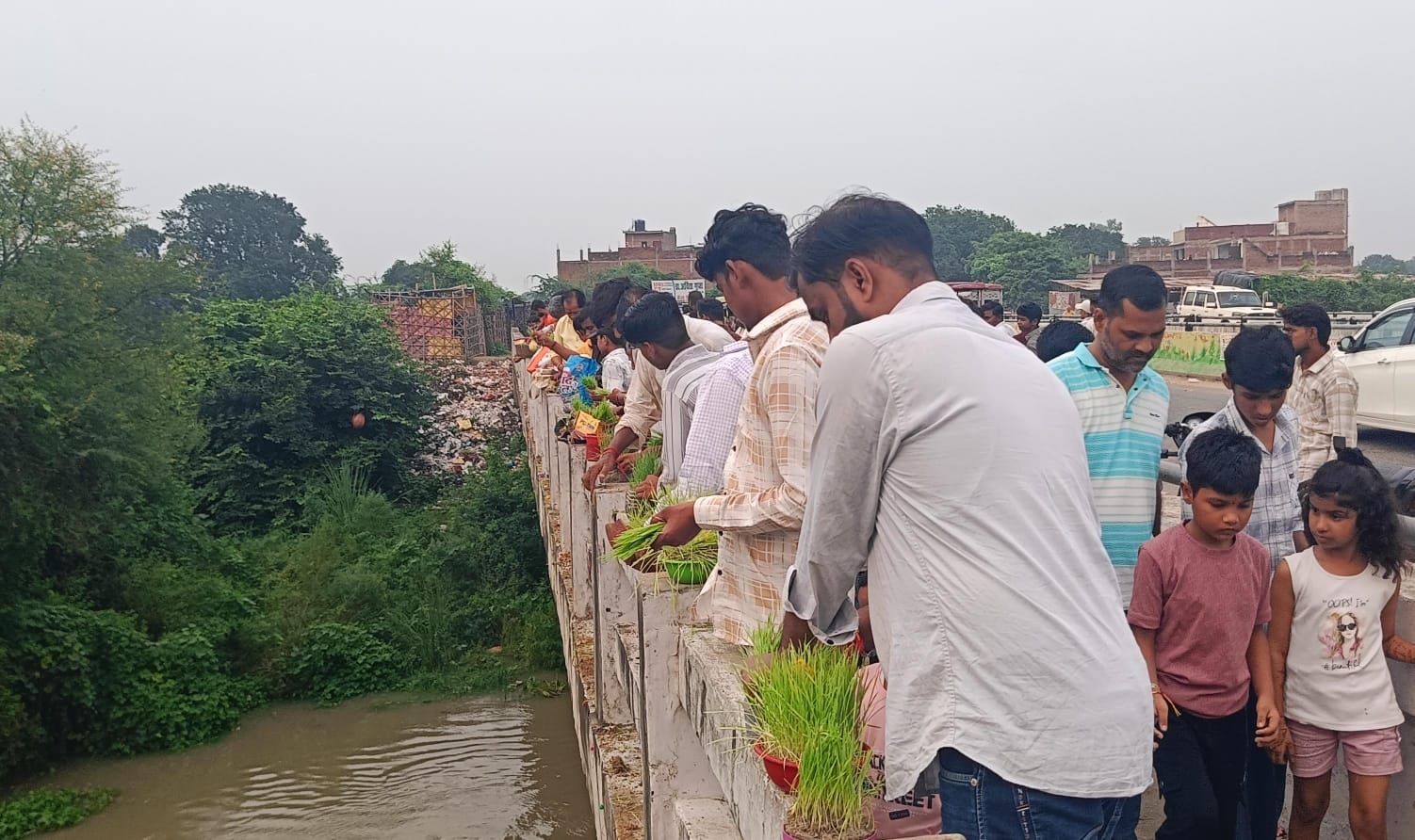 फोटो-47- बिधूना में नदी पुल पर भुजरियां विसर्जित करते लोग।संवाद