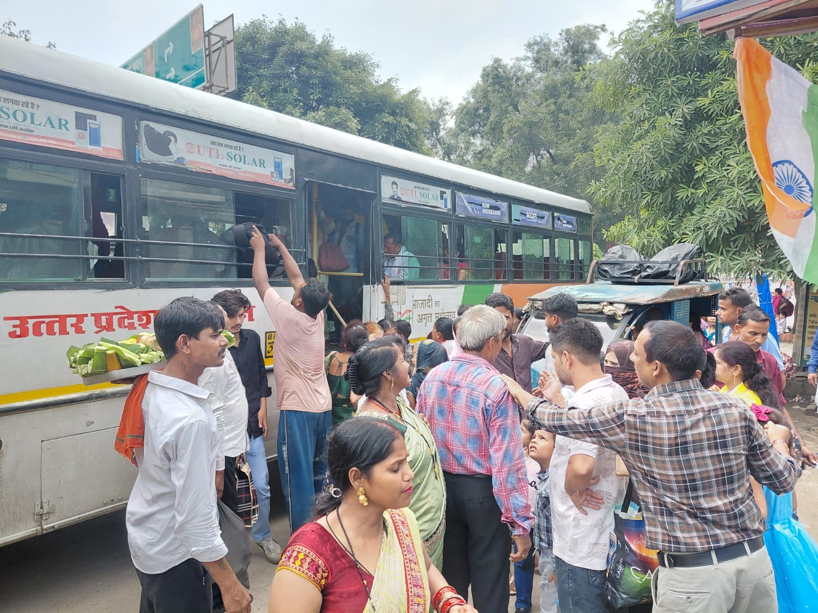 बस के आने पर सीट पाने के लिए खिड़की से बस में बैग रखता युवक। संवाद