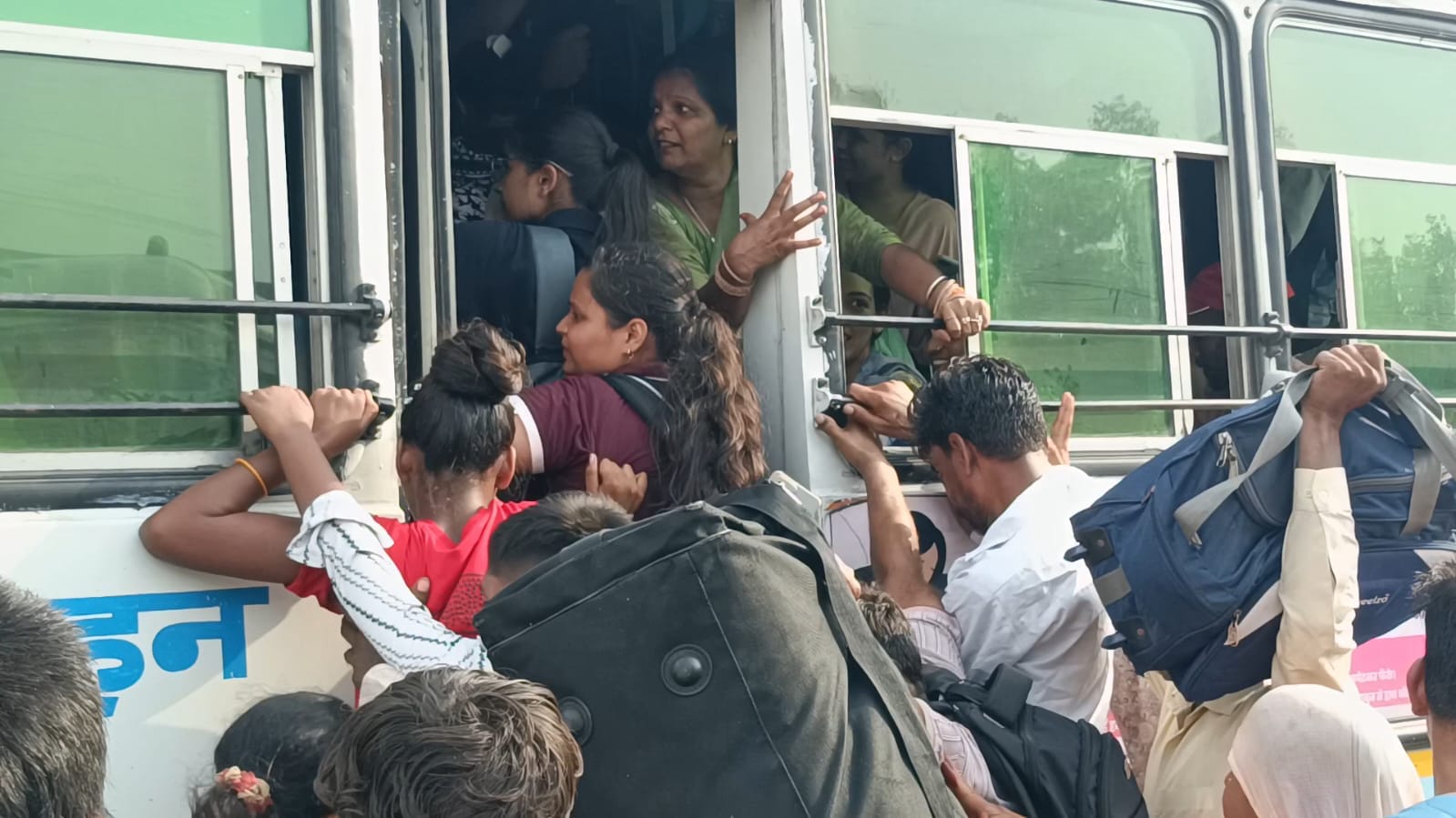 बस में चढ़ते समय धक्का मुक्की करते हुए यात्री। संवाद