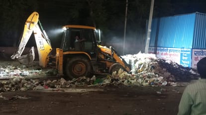 तोशाम रोड स्थित आईटीआई पर रात में पुलिस के पहरे में सड़क से कूड़ा उठाती जेसीबी। 