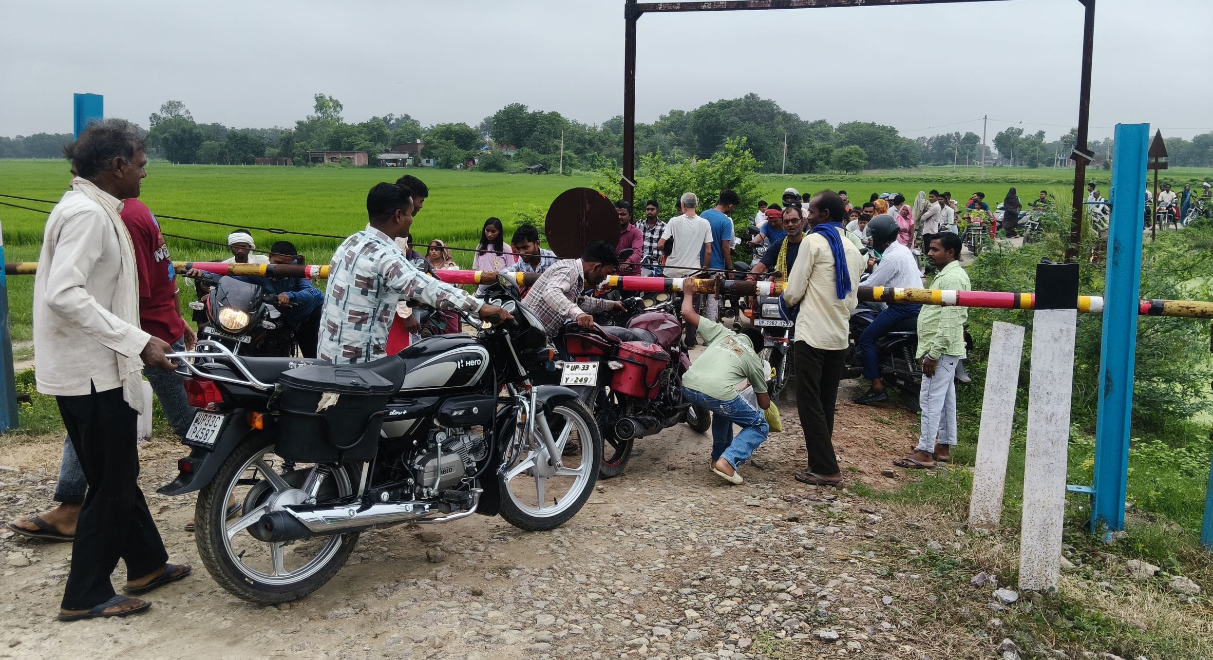 पचखरा गांव स्थित रेलवे क्रॉसिंग का गेट खराब होने के बाद इस तरह गेट के नीचे से बाइक निकालते लोग।