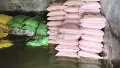 पानी में डूबी गोदाम के भीतर रखी उर्वरक, बिजली की मोटर पंप से पानी निकालते ग्रामीण। संवाद,