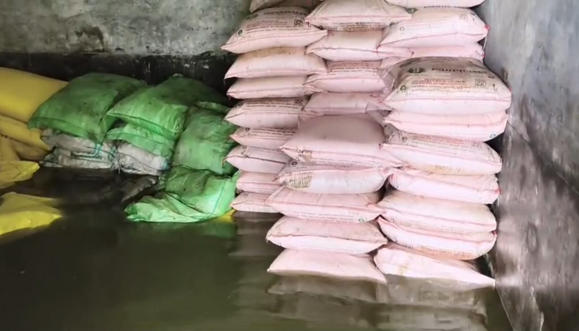 पानी में डूबी गोदाम के भीतर रखी उर्वरक, बिजली की मोटर पंप से पानी निकालते ग्रामीण। संवाद,