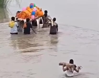 अंतिम संस्कार करने के लिए पानी भरे रास्ते से अर्थी लेकर जाते हुए लोग।