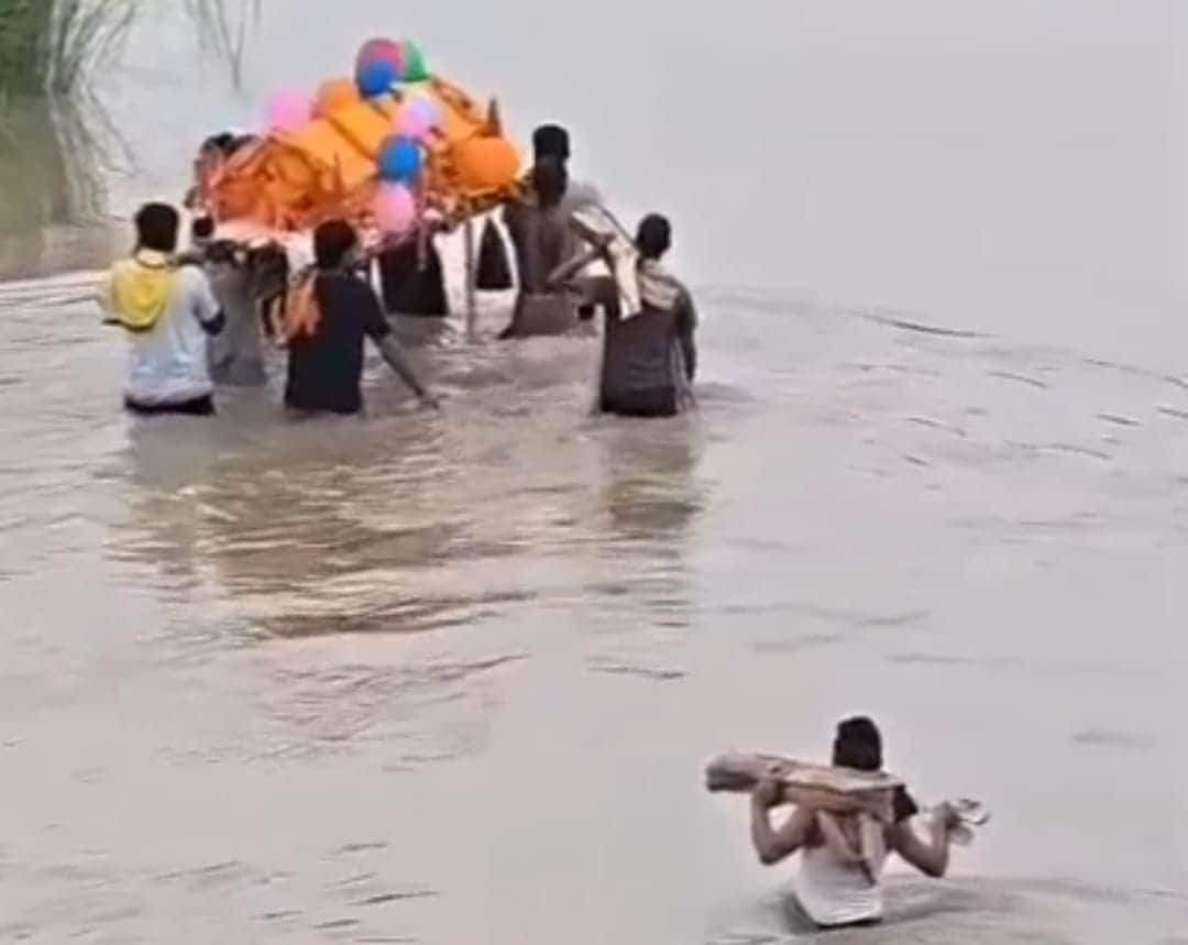 अंतिम संस्कार करने के लिए पानी भरे रास्ते से अर्थी लेकर जाते हुए लोग।